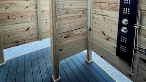A wooden deck with a black metal shower enclosure.