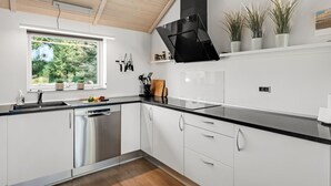 A modern kitchen with white cabinets, a black countertop, and a window overlooking greenery.