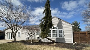 Une maison à deux étages avec un porche à l’avant, un garage et une clôture en bois.