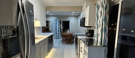 A modern kitchen with stainless steel appliances, white cabinetry, and a central island.