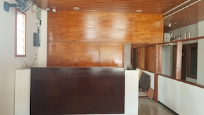 A modern kitchen with wooden cabinets, a large dark countertop, and a ceiling fan. - OYO 93709 Rose Inn 2 (Medan)