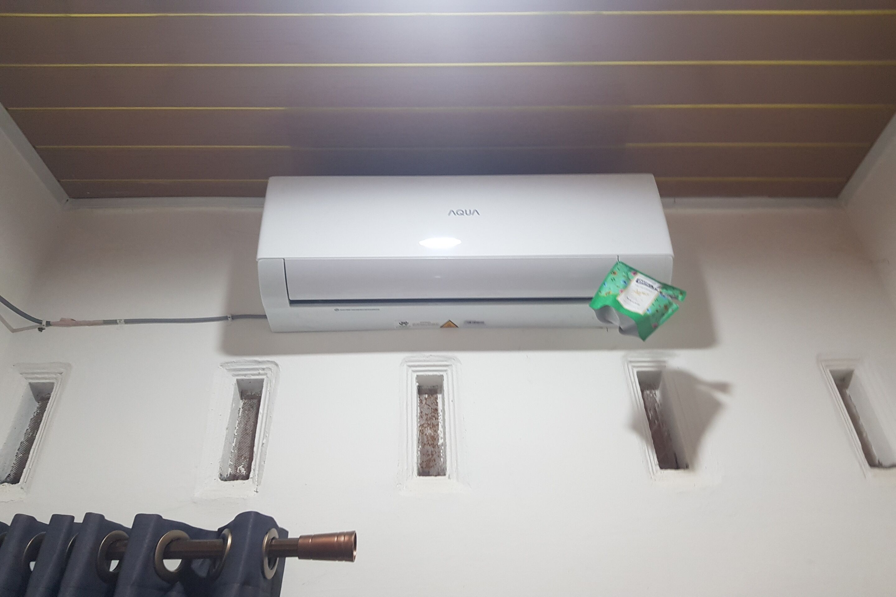 A white air conditioning unit mounted on a wall with a visible brand name.