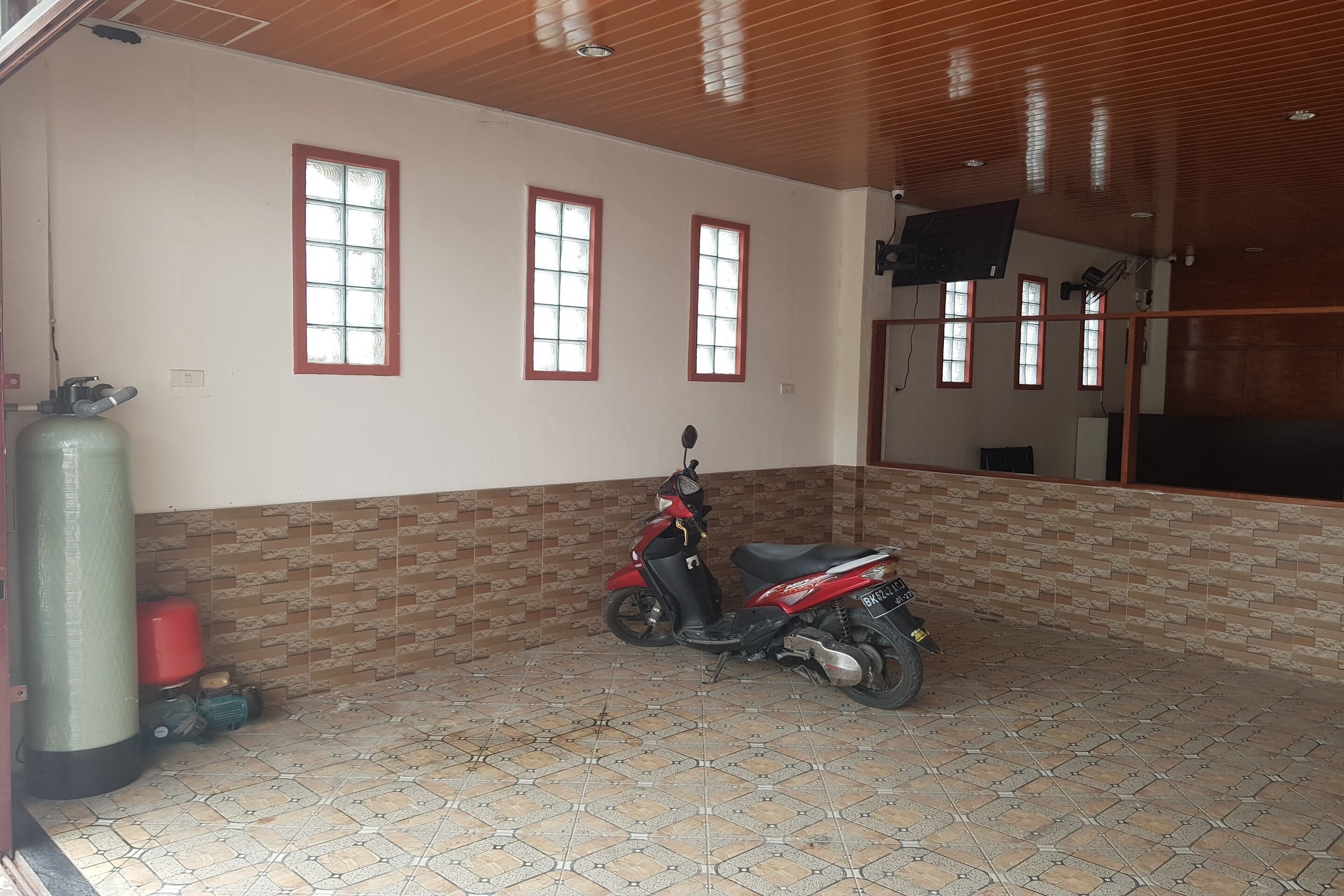 A room with a tiled floor, a scooter, a water dispenser, and a window with a red frame.