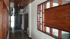 A hallway with wooden paneling and a large window with a grid design. - OYO 93709 Rose Inn 2 (Medan)