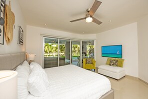 A bedroom with a bed, a ceiling fan, a TV, and a view of the outdoors.