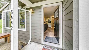 A house entrance with a wooden bench outside, a welcome mat, and a door leading to a kitchen area. - Storybook Tacoma Cottage Escape (Tacoma)