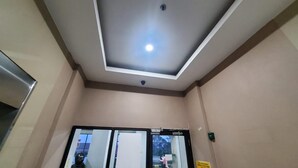 A room with a recessed ceiling light, a door with a glass panel, and a yellow sign on the wall. - Collection O 93708 Tamansari Panoramic Apartment By Rasya Rooms (Bandung)