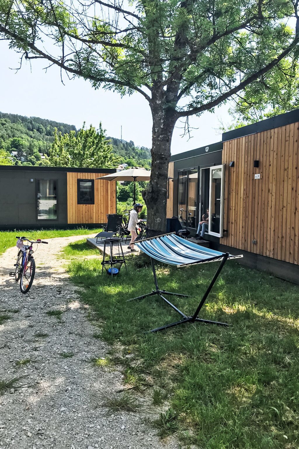 Un espace extérieur moderne avec un hamac, un vélo et une table placée sous un arbre.