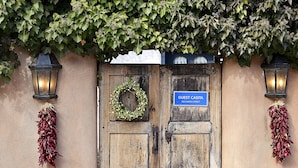 Une porte en bois avec une pancarte indiquant « Maison d’hôtes », une guirlande et des piments séchés suspendus de chaque côté.