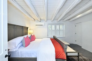 Ein Schlafzimmer mit einem großen Bett, einem Holz-Kopfteil, einem Nachttisch und einem Fenster mit Rollläden.