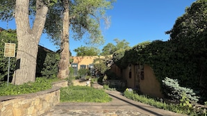 Un chemin de pierre mène à un bâtiment doté d’un mur en pierre et d’un panneau indiquant un parking privé situé au 300, rue Garcia.