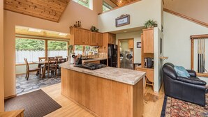 A spacious kitchen with wooden cabinets, a central island, and a dining area with chairs. - Majestic Sequim Vacation Home near Sequim Bay (Sequim)