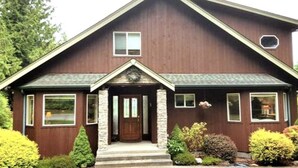 A two-story house with a front porch, a central door, and a small window above the door. - Majestic Sequim Vacation Home near Sequim Bay (Sequim)