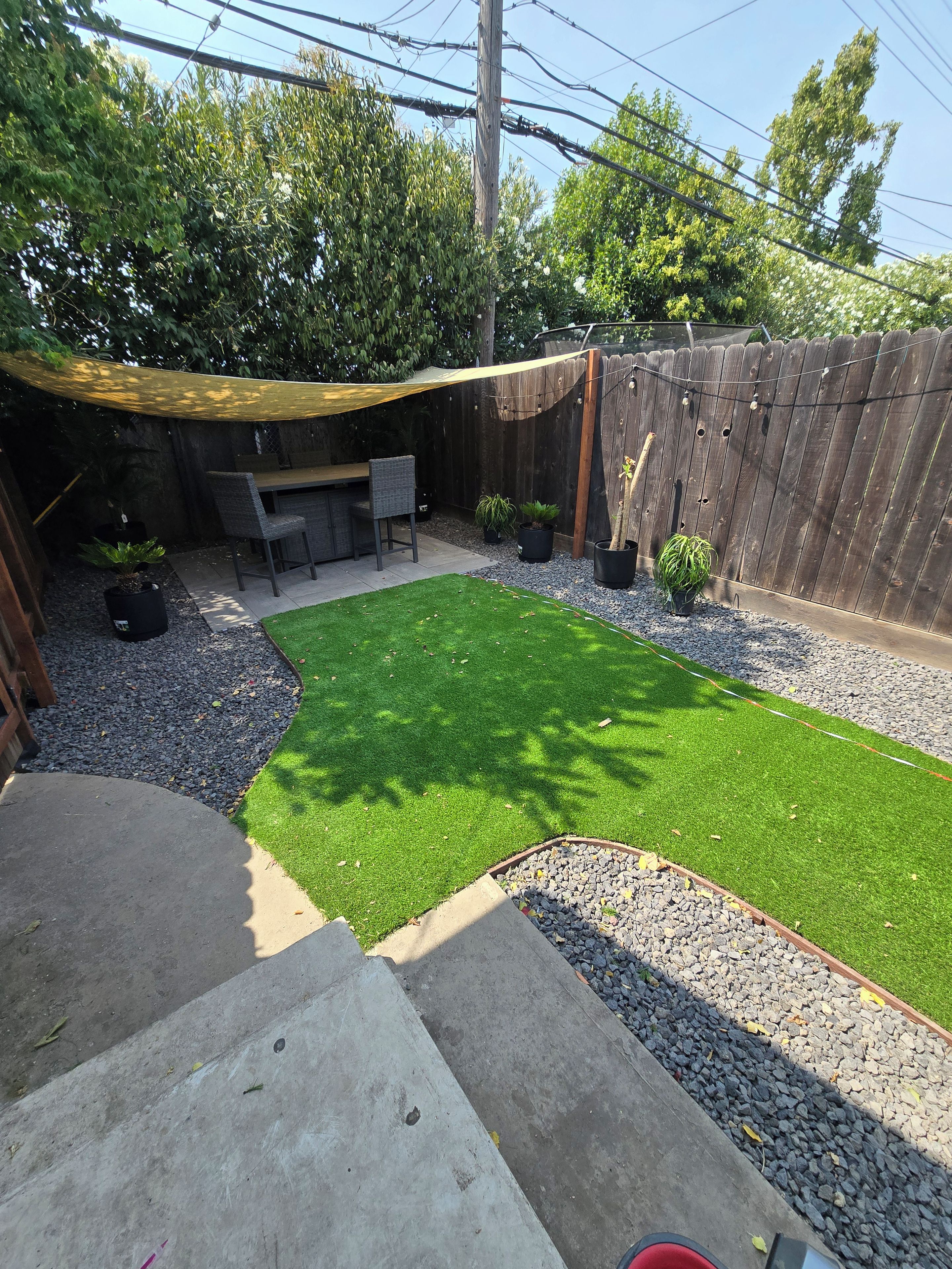 Un giardino sul retro con prato verde, un patio in legno e una zona salotto.