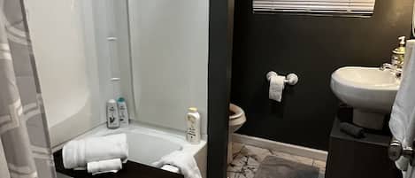 A bathroom with a bathtub, a sink, and a window with blinds.