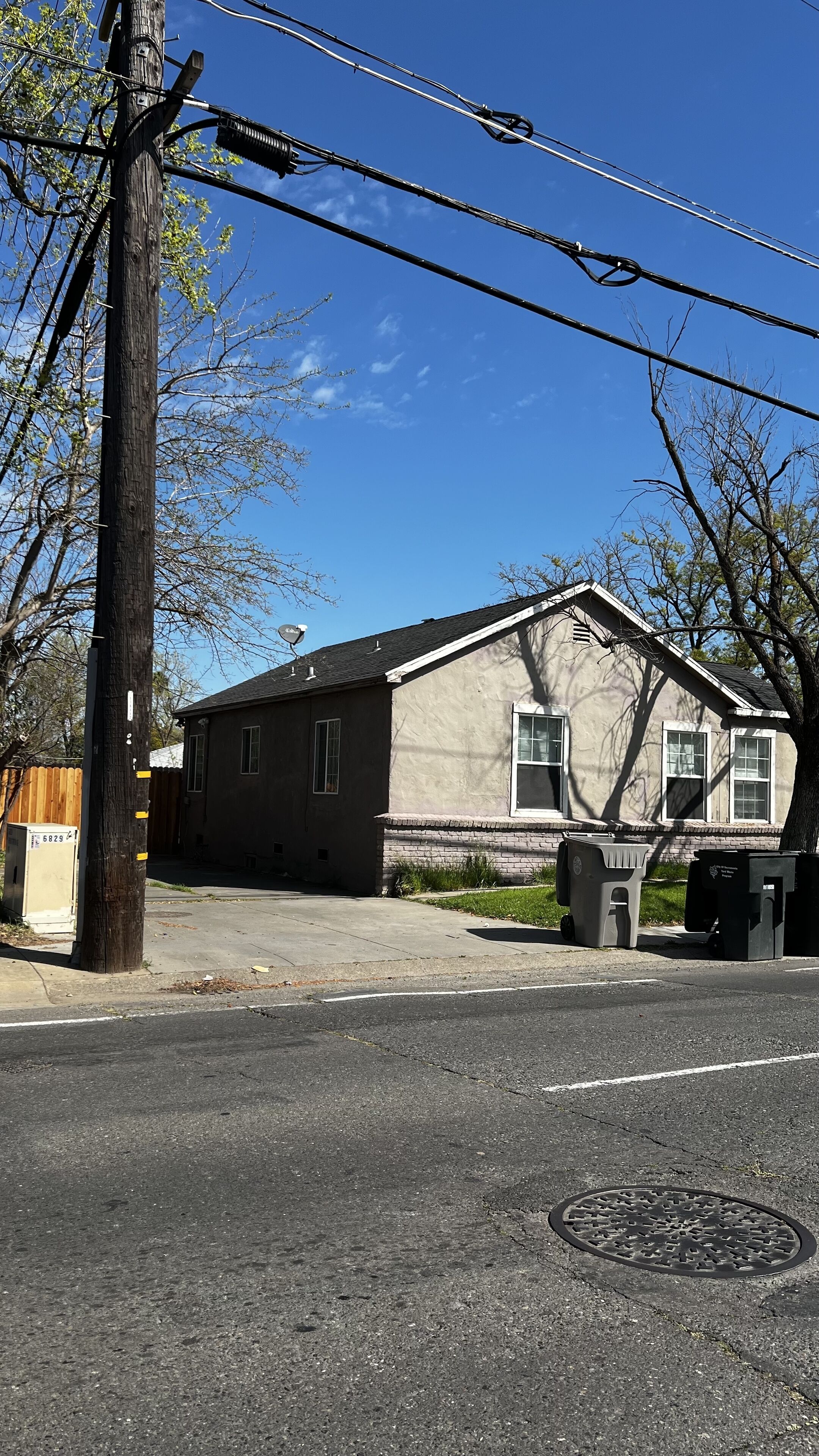 A two-story house with a garage, a visible manhole cover, and a street in front.
