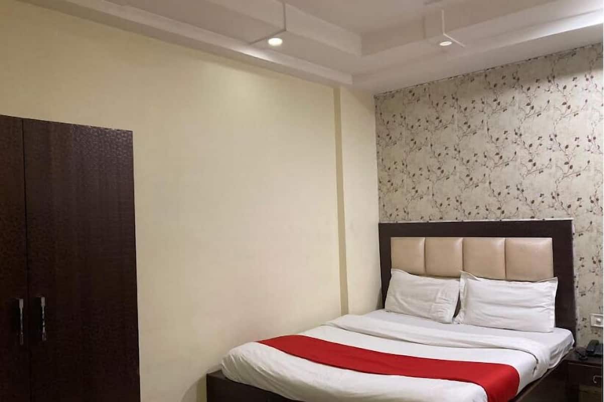 A bedroom with a bed, a wardrobe, and a wall with a floral pattern.