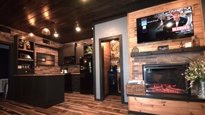 Una sala de estar moderna con chimenea, un televisor montado en la pared y una zona de bar.