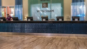 Vastaanottotiski, jossa on Wyndham-logo, vastaanottovirkailija ja sisäänkirjautumistiski.