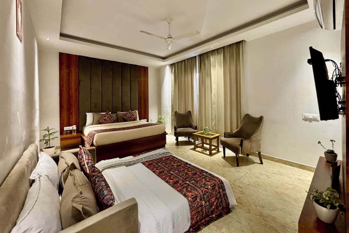 Een hotelkamer met een groot bed, twee fauteuils, een tafeltje en een plafondventilator.