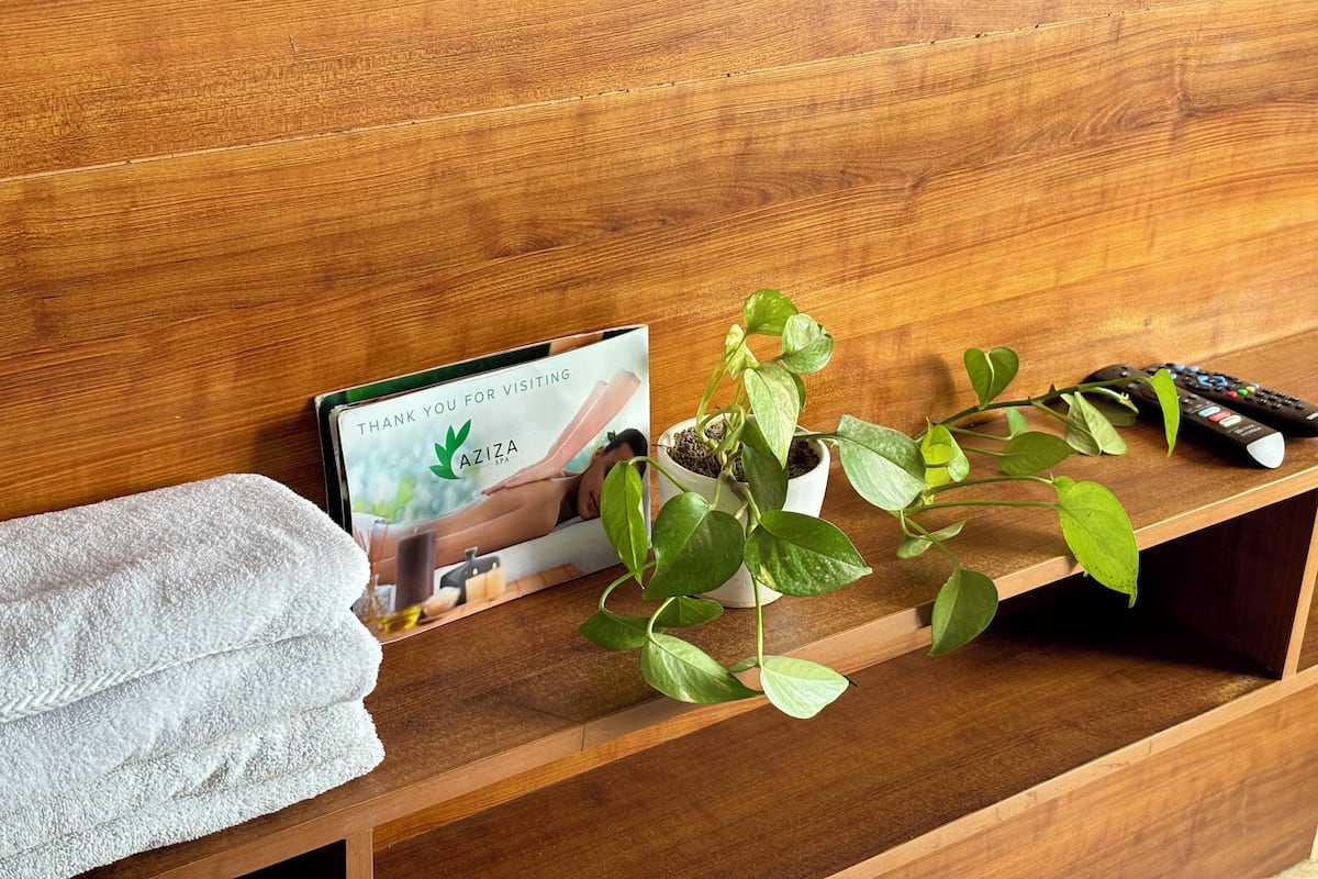 Een houten plank met een handdoek, een bedankkaartje, een bloempot en twee afstandsbedieningen.