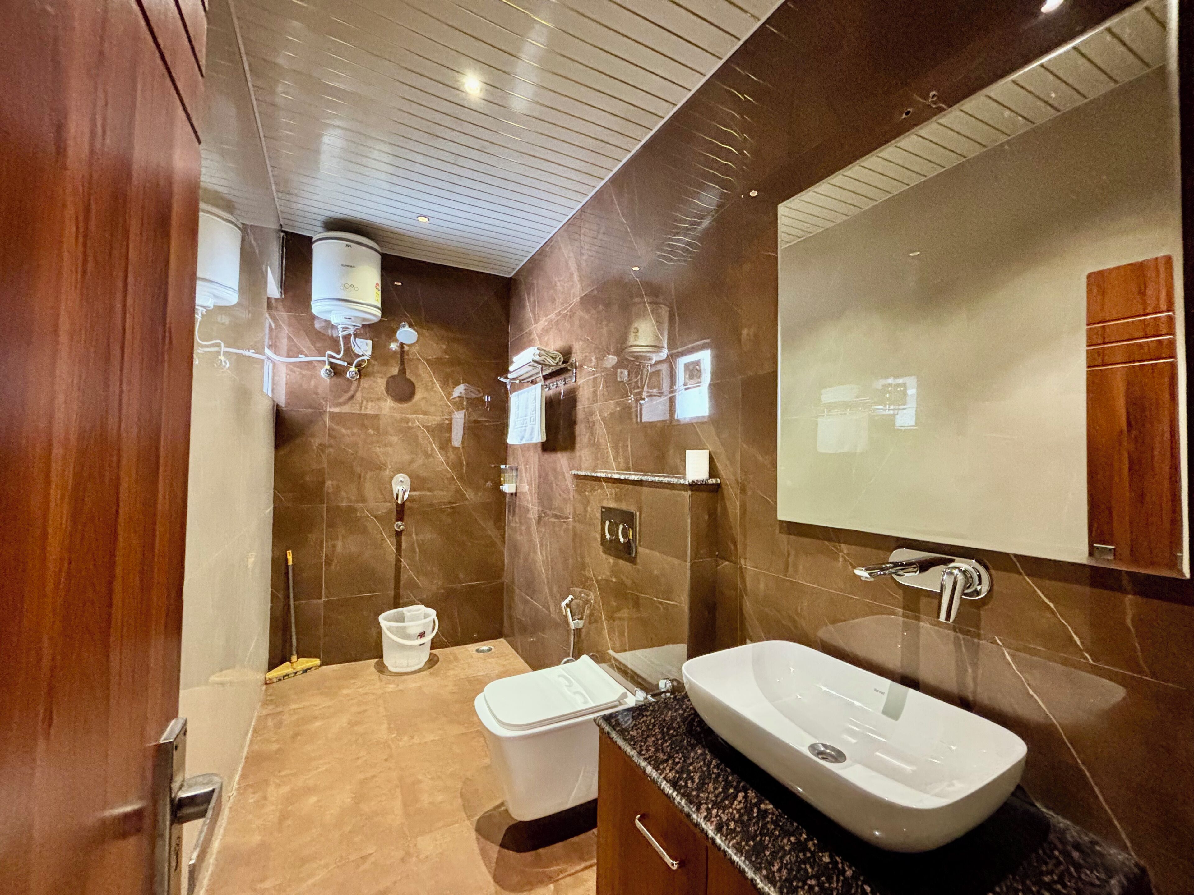 A modern bathroom with a large mirror, a freestanding sink, and a shower area.