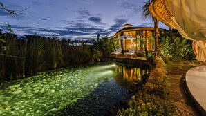 Un resort con piscina, sillas de descanso y una estructura con techo de paja.