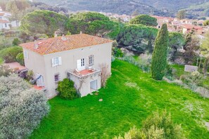 Una casa de dos pisos con techo de tejas, un pequeño porche y un césped bien cuidado.