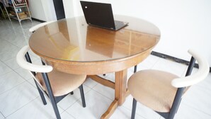 Een ronde glazen tafel met een laptop erop, omringd door vier stoelen met witte leuningen.