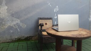 Een laptop op een houten tafel, met een stoel ernaast.