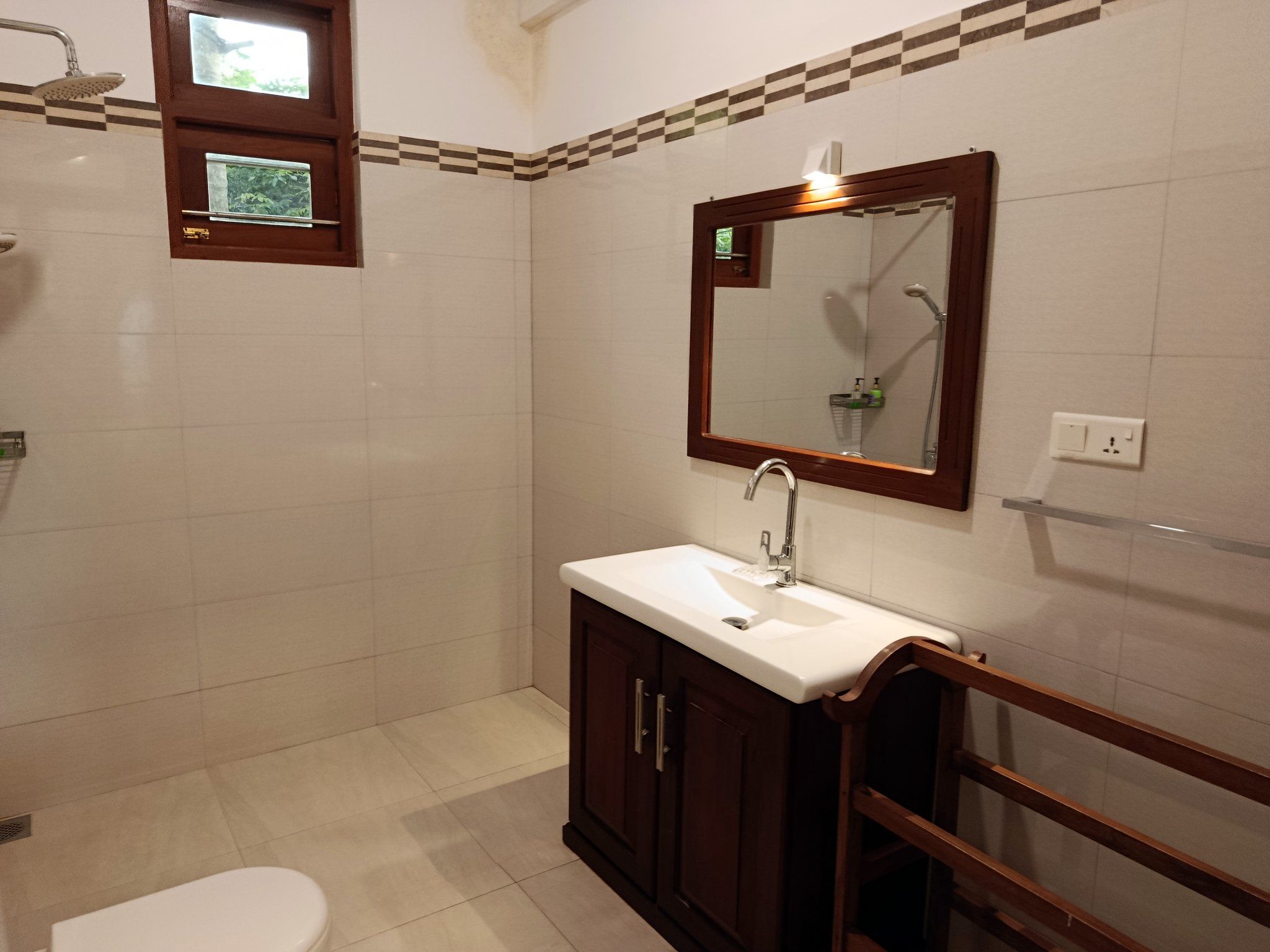 Un baño con lavamanos blanco, un espejo y una ducha.