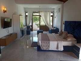 Un dormitorio moderno con una cama grande, televisión, escritorio y zona de estar.