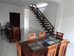 A dining area with a glass-top table, wooden chairs, and a staircase with wooden steps. - Piyum Villa Kosgoda (Kosgoda)