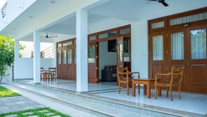 A covered outdoor area with wooden doors, a seating area with chairs, and a small table. - Piyum Villa Kosgoda (Kosgoda)