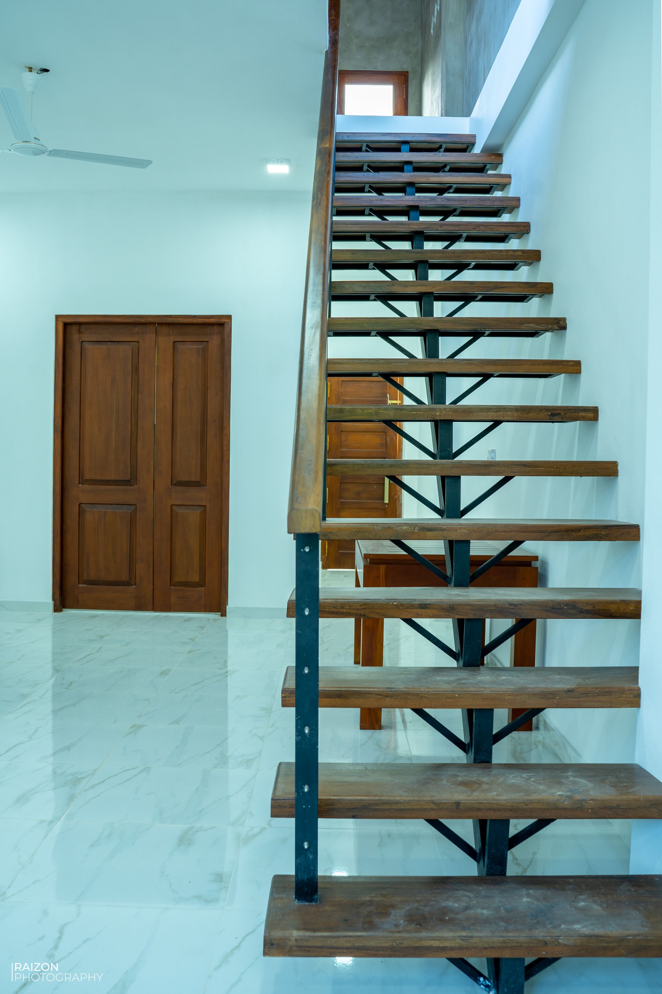 Una escalera de madera con soportes metálicos, que lleva a una puerta en la parte superior.