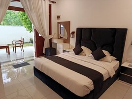 Habitación de hotel con una cama grande, una mesita de noche, un espejo y vistas al exterior.
