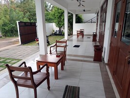 Un espacio exterior techado con una mesa, sillas, un banco y una planta en maceta.