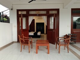 Una habitación con una cama, dos sillas de madera, una mesita y un armario.