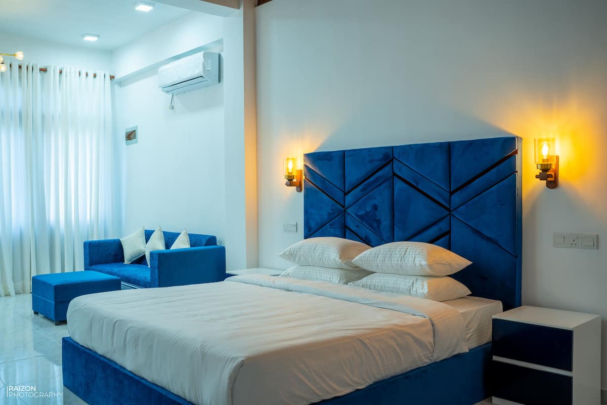 Ein modernes Schlafzimmer mit einem großen Bett, einem blauen Kopfteil und zwei Nachttischlampen.