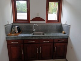 Una cocina con encimera de granito, un lavamanos y armarios de madera.