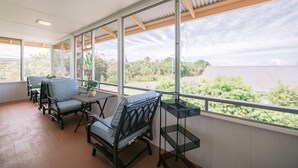 Un patio couvert avec des sièges et une vue sur la verdure.