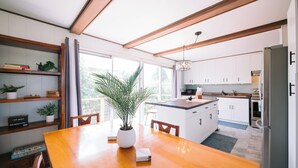 Une cuisine moderne avec des meubles blancs, une table à manger en bois et une plante en pot.