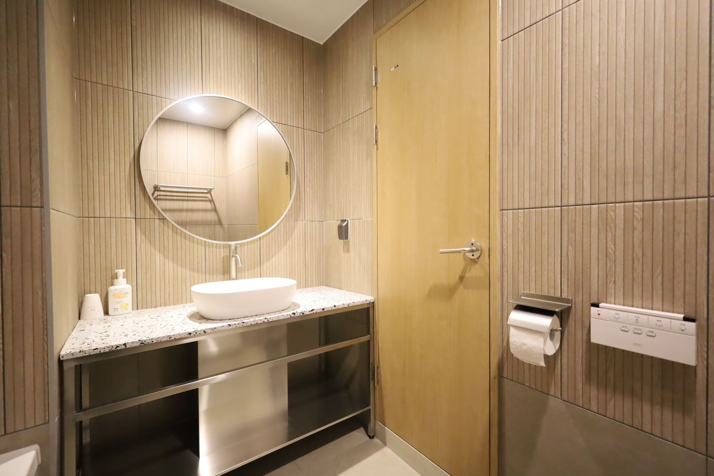 Un baño moderno con un espejo redondo, un lavabo, un inodoro y un perchero para toallas.