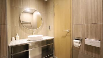 Un baño moderno con un espejo redondo, un lavabo, un inodoro y un perchero para toallas.