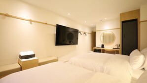 A hotel room with a large bed, a bedside table with a lamp, a TV mounted on the wall, a desk with a chair, and a round mirror. - H AVENUE  Jecheon Station (Jecheon)