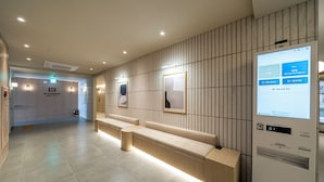 A modern hotel lobby with a reception desk, seating area, and a digital information kiosk. - H AVENUE  Jecheon Station (Jecheon)