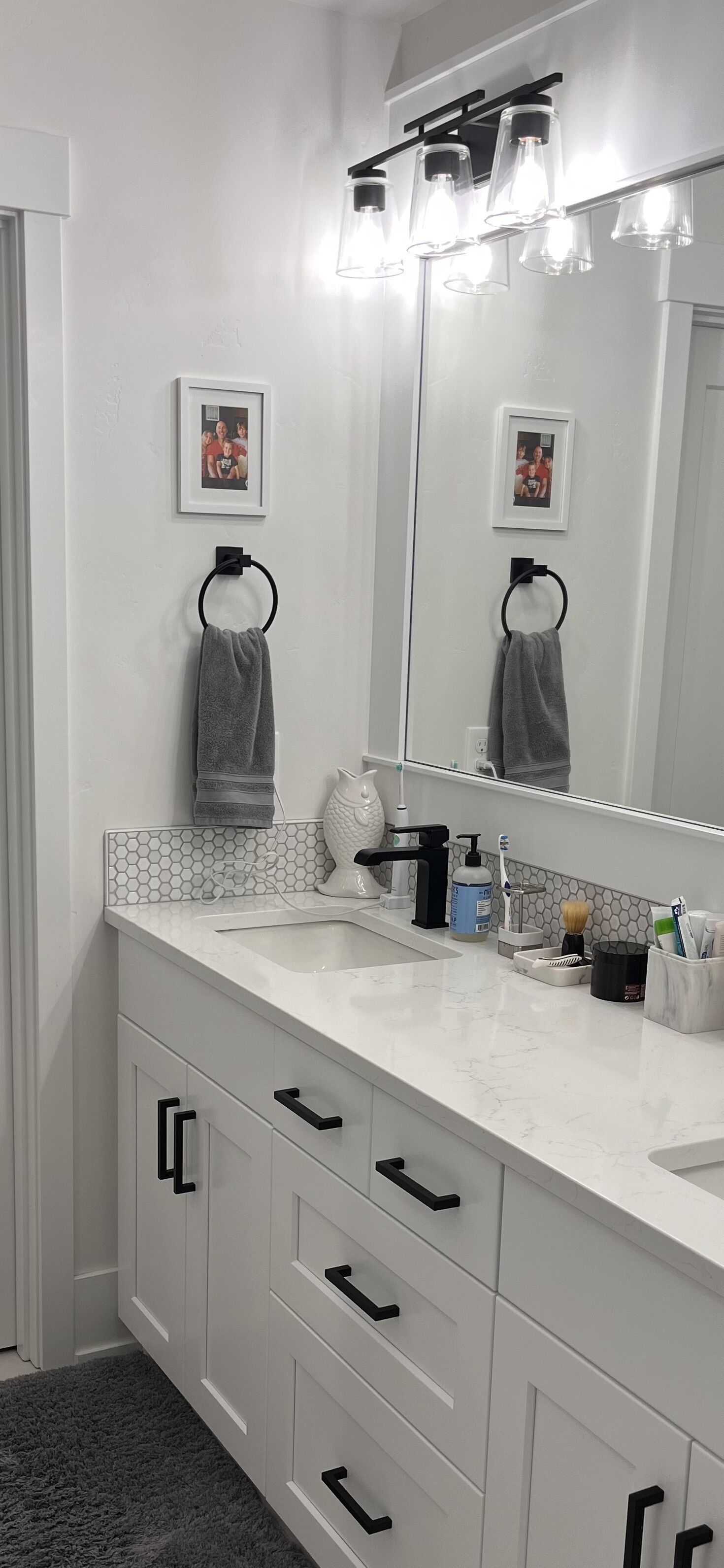 A bathroom with a white vanity, a large mirror, and a towel ring.