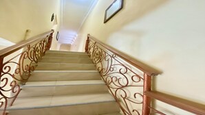 A staircase with ornate metal railings and a plain wall. - Hotel O Kenzie Bunkbed Syariah (Klaten)