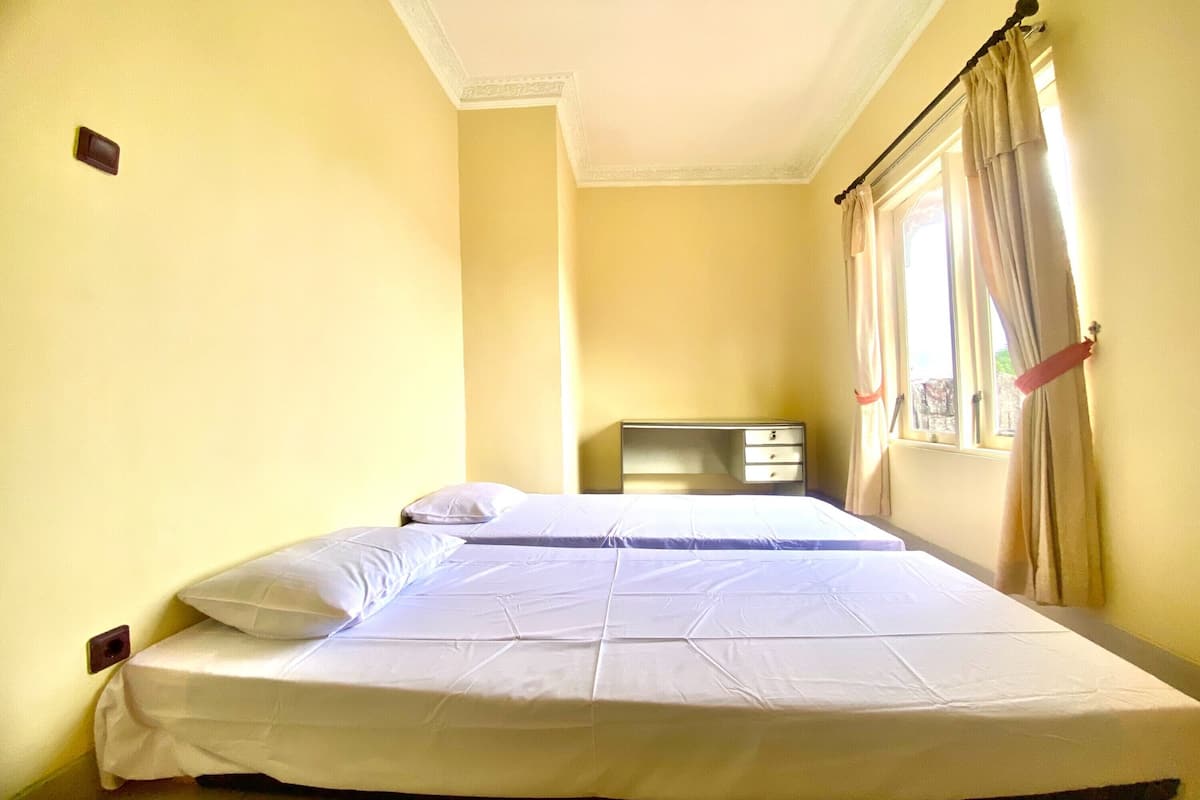 A hotel room with two beds, a nightstand, and a window with curtains.