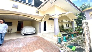 A two-story house with a covered carport and a front porch with potted plants. - Hotel O Kenzie Bunkbed Syariah (Klaten)